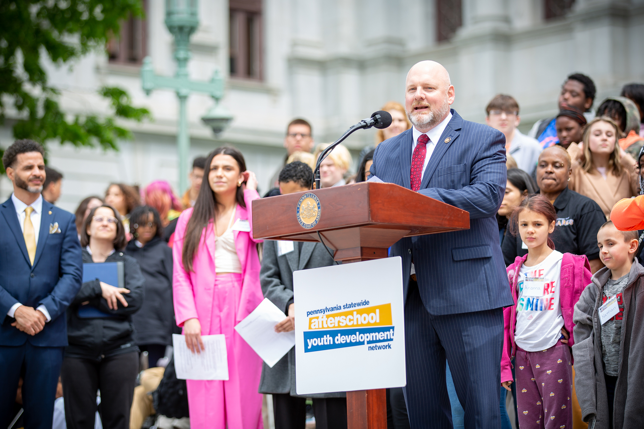 Representative Doyle Heffly standing at podium on Capitol steps and addressing attendees.