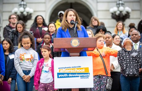 Representative Elizabeth Fiedler addressing attendees of rally, on Capitol steps. Group of students standing behind her.