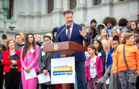 Senator Mike Regan speaking to attendees, with group of students and afterschool leaders standing behind him, on Capitol steps