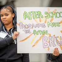 youth holding homemade poster stating "Afterschool programs make the future bright"