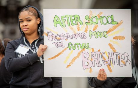 youth holding homemade poster stating "Afterschool programs make the future bright"