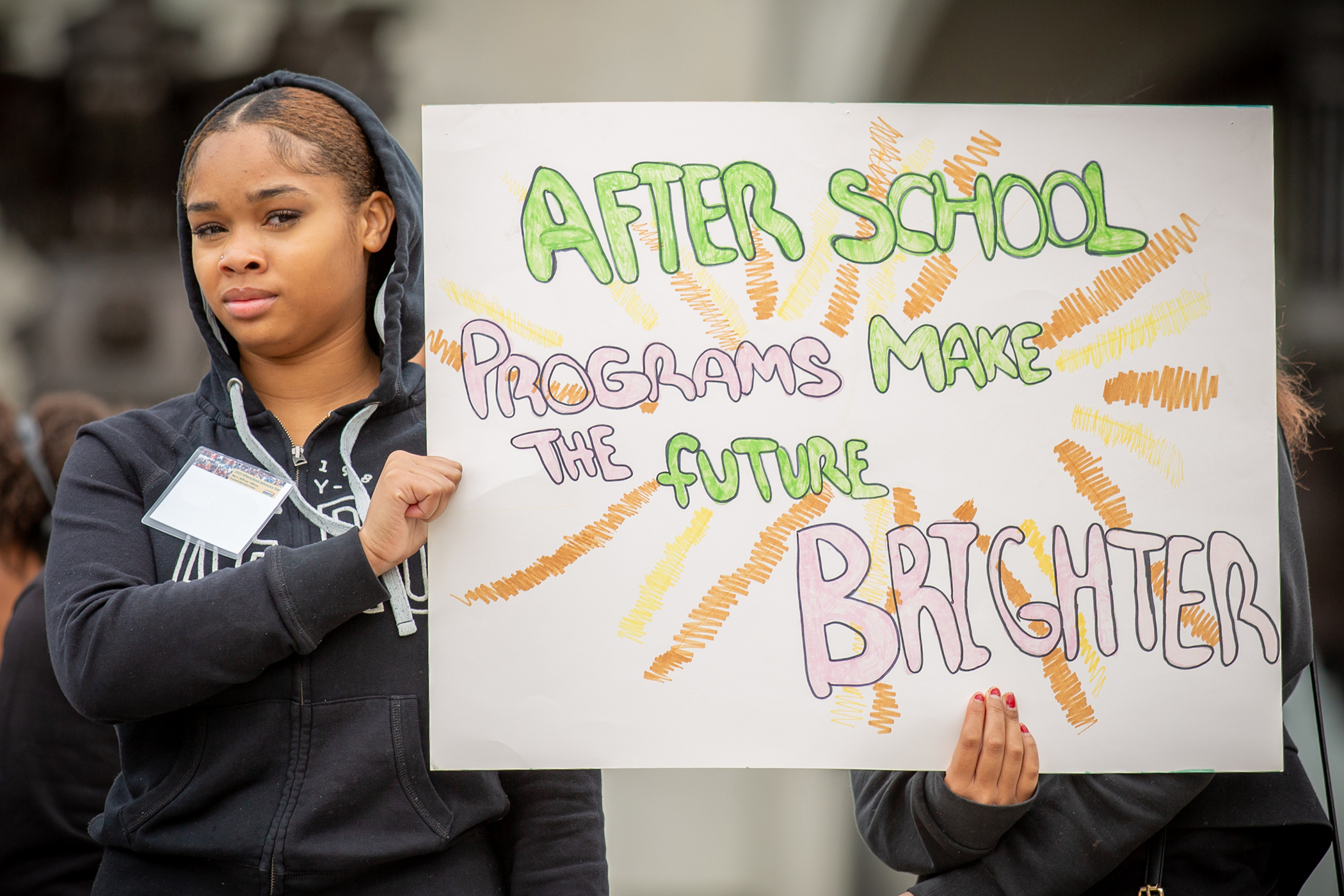 youth holding homemade poster stating "Afterschool programs make the future bright"